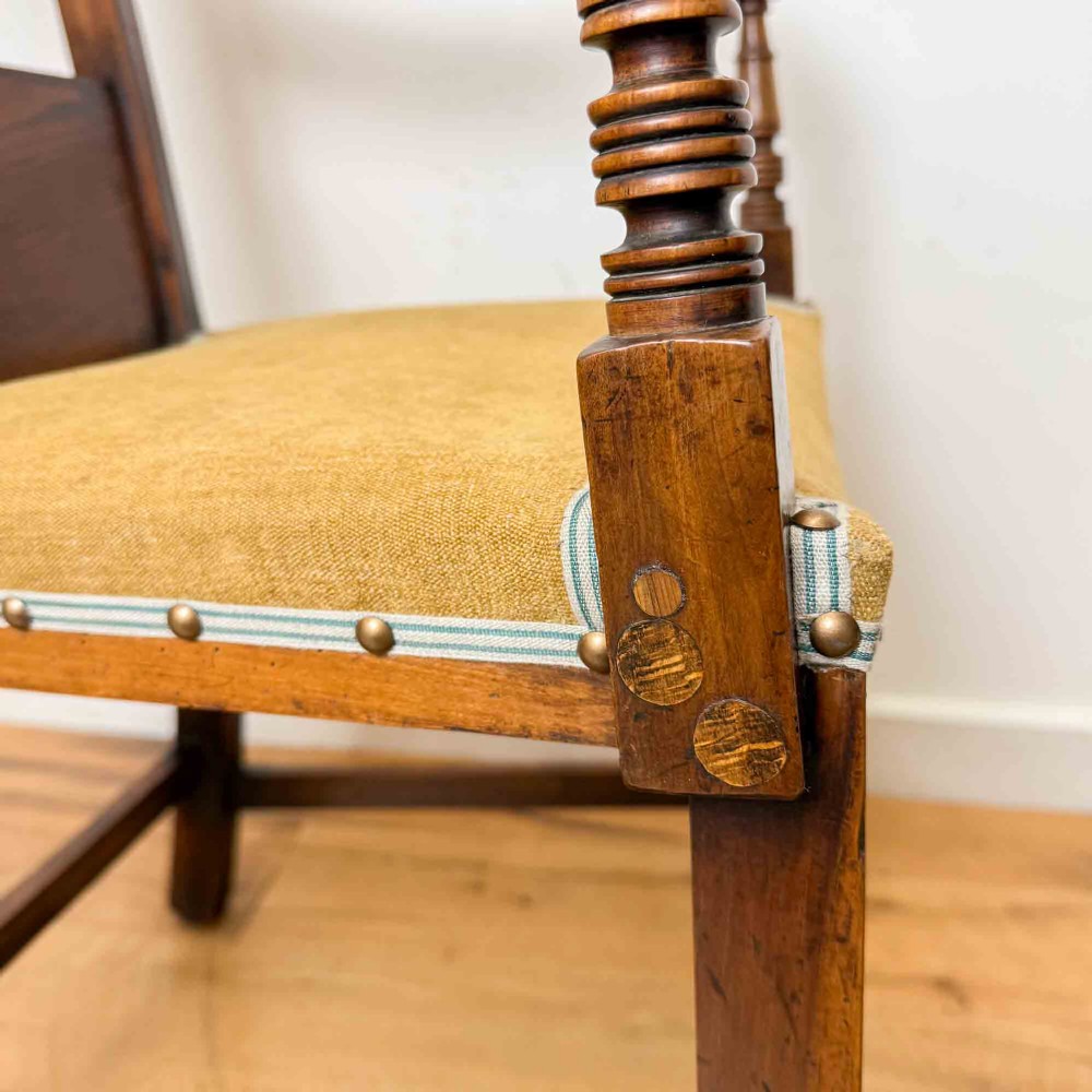A Regency period high back open armchair crafted from fruitwood and elm with turned arm supports and a textured ochre upholstered seat. View IX