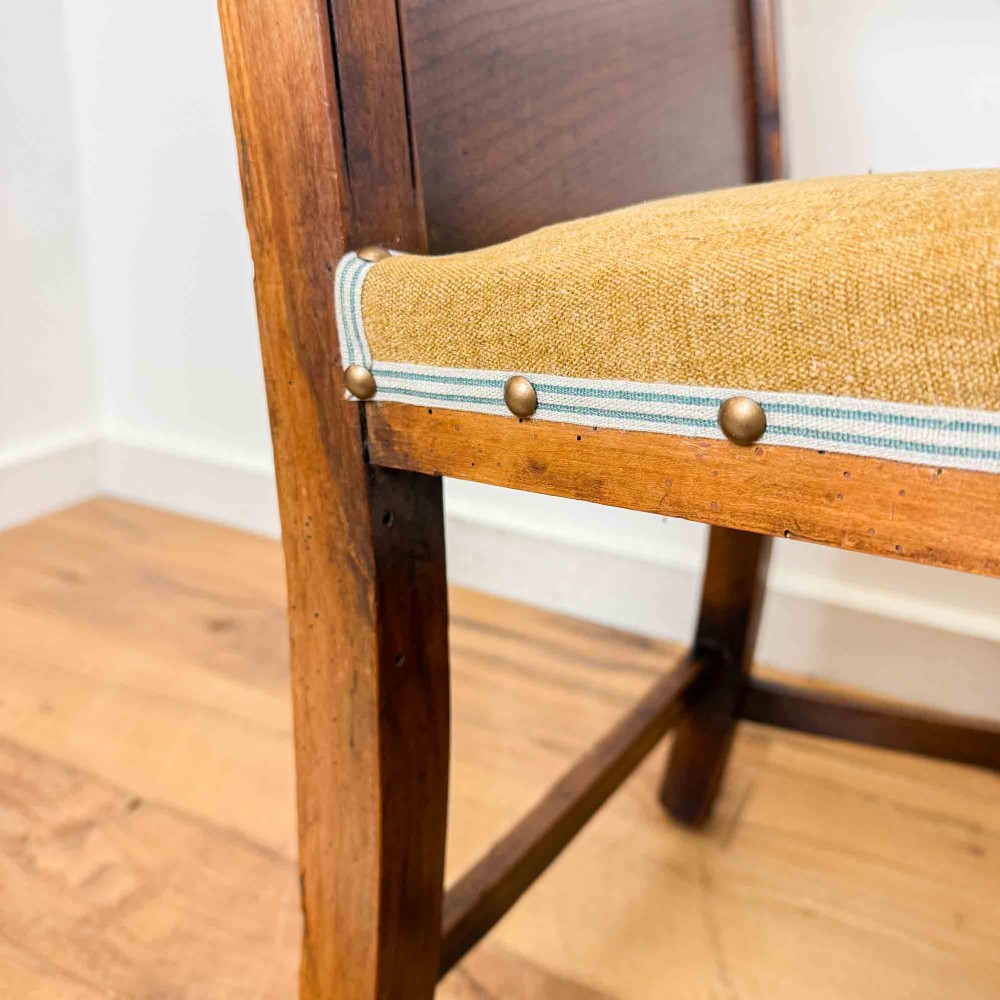 A Regency period high back open armchair crafted from fruitwood and elm with turned arm supports and a textured ochre upholstered seat. View X