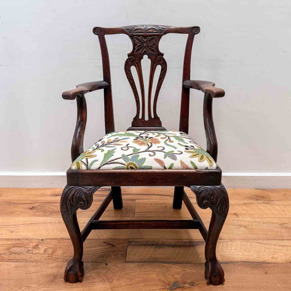 A dark carved oak armchair with cabriole legs, ball and claw feet, a carved splat back, and a crewelwork embroidered seat pad. View VII