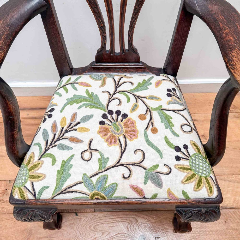A dark carved oak armchair with cabriole legs, ball and claw feet, a carved splat back, and a crewelwork embroidered seat pad. View XIII
