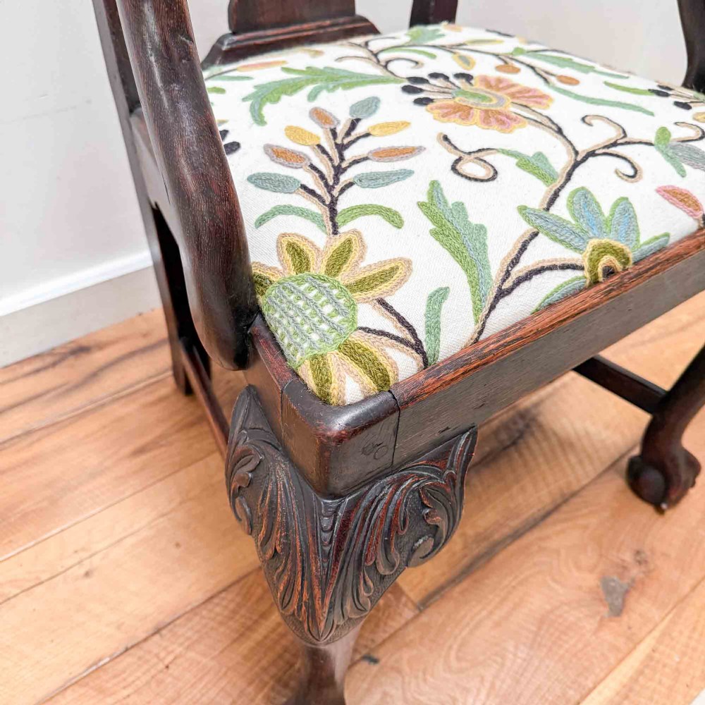 A dark carved oak armchair with cabriole legs, ball and claw feet, a carved splat back, and a crewelwork embroidered seat pad. View XV