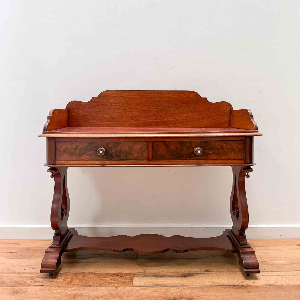 A Victorian mahogany writing table featuring a raised gallery back, two drawer fronts with wooden knobs, shaped lyre supports, and a low stretcher base on castors. View II