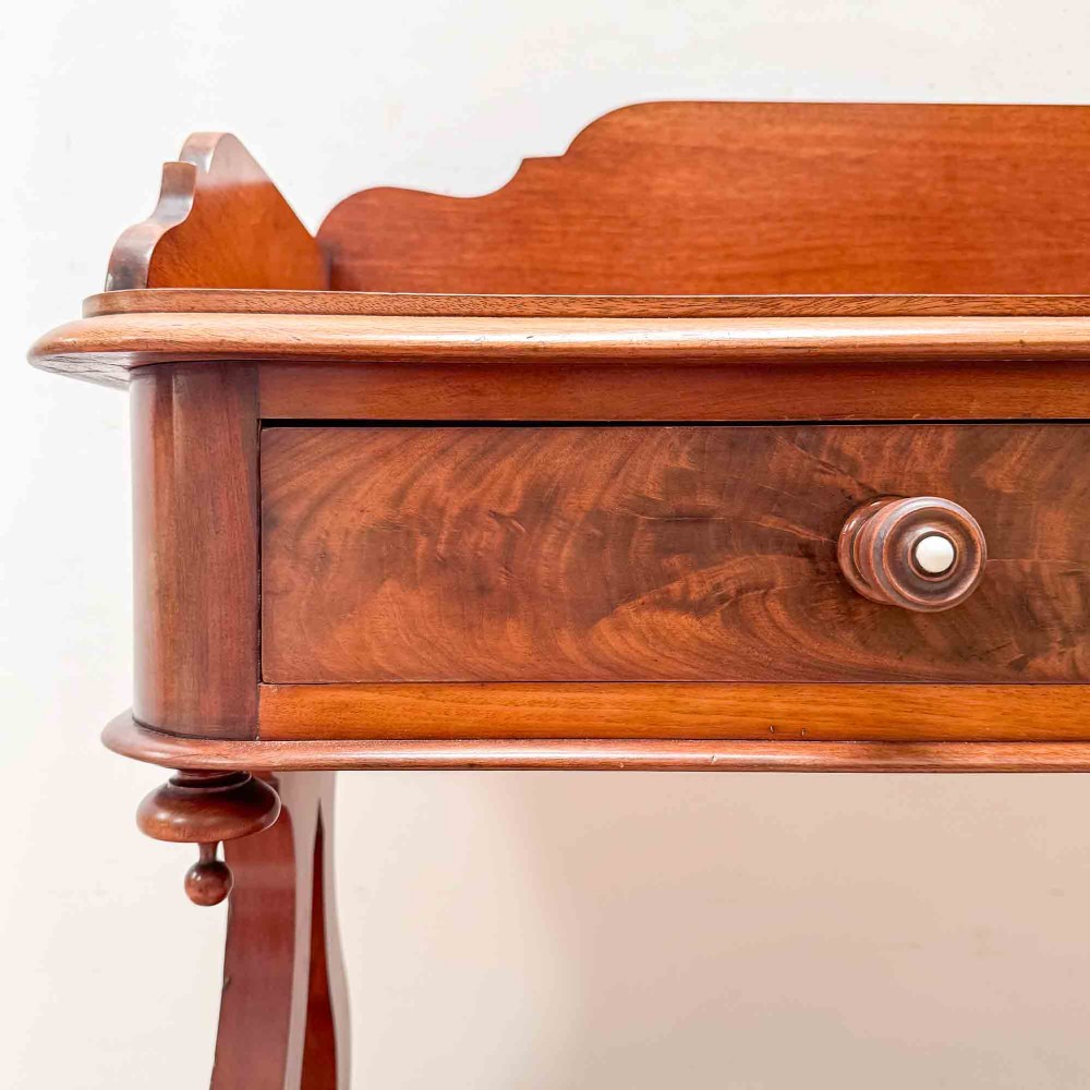 A Victorian mahogany writing table featuring a raised gallery back, two drawer fronts with wooden knobs, shaped lyre supports, and a low stretcher base on castors. View III