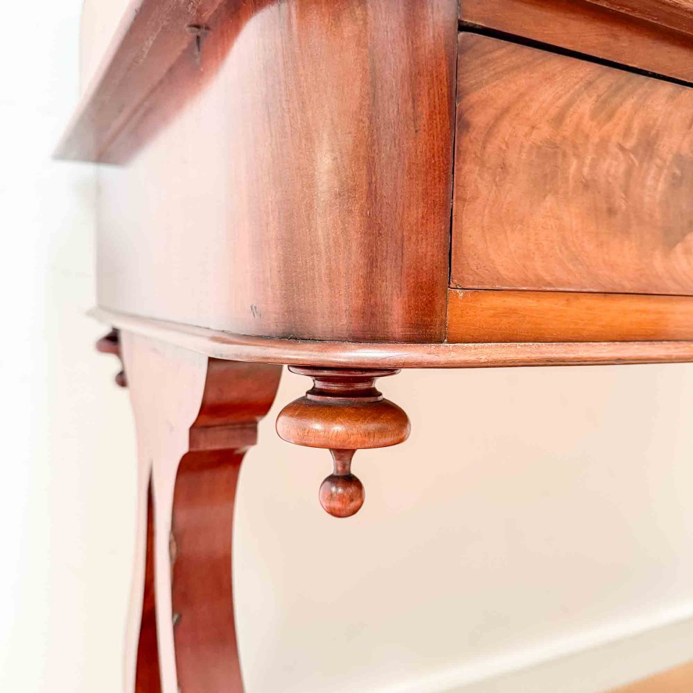 A Victorian mahogany writing table featuring a raised gallery back, two drawer fronts with wooden knobs, shaped lyre supports, and a low stretcher base on castors. View V
