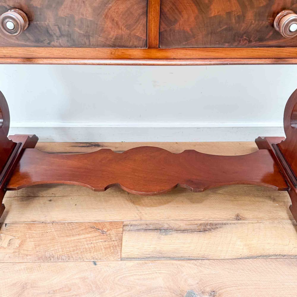 A Victorian mahogany writing table featuring a raised gallery back, two drawer fronts with wooden knobs, shaped lyre supports, and a low stretcher base on castors. View VII