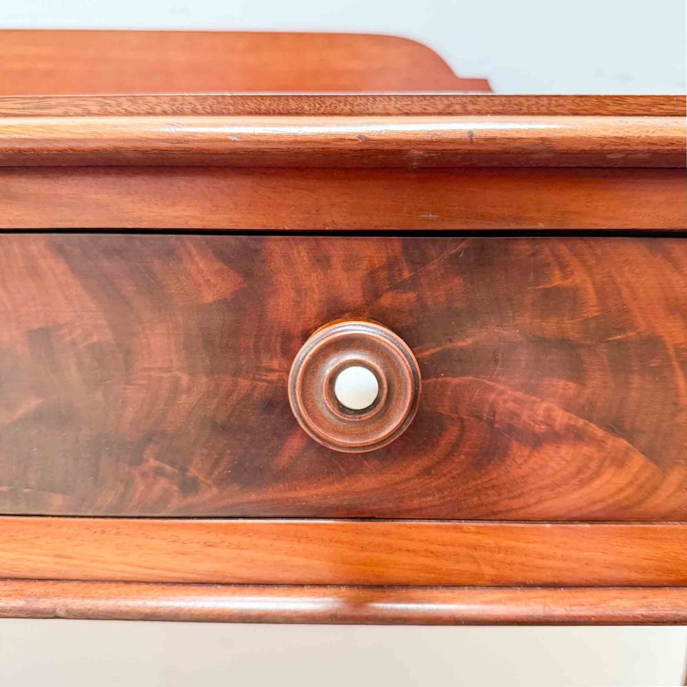 A Victorian mahogany writing table featuring a raised gallery back, two drawer fronts with wooden knobs, shaped lyre supports, and a low stretcher base on castors. View XI