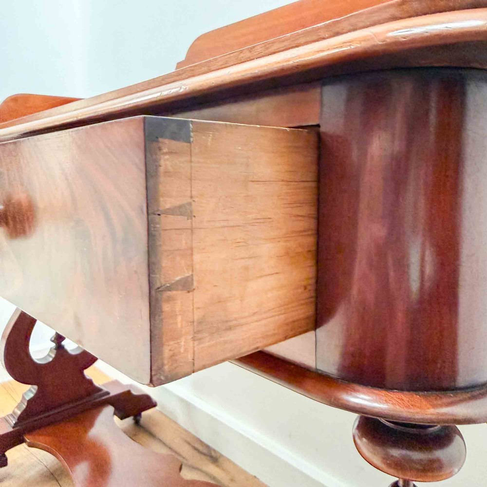 A Victorian mahogany writing table featuring a raised gallery back, two drawer fronts with wooden knobs, shaped lyre supports, and a low stretcher base on castors. View XII
