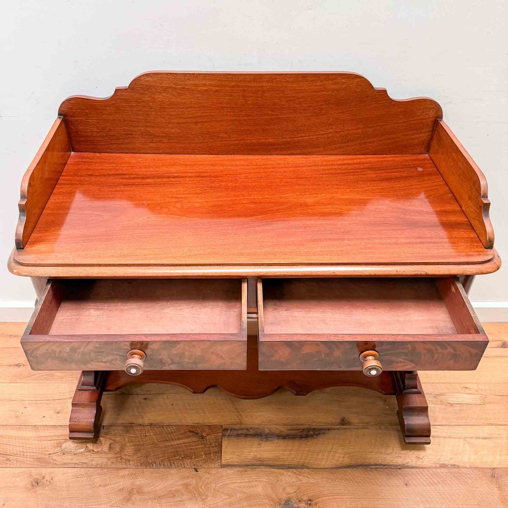 A Victorian mahogany writing table featuring a raised gallery back, two drawer fronts with wooden knobs, shaped lyre supports, and a low stretcher base on castors. View XIII