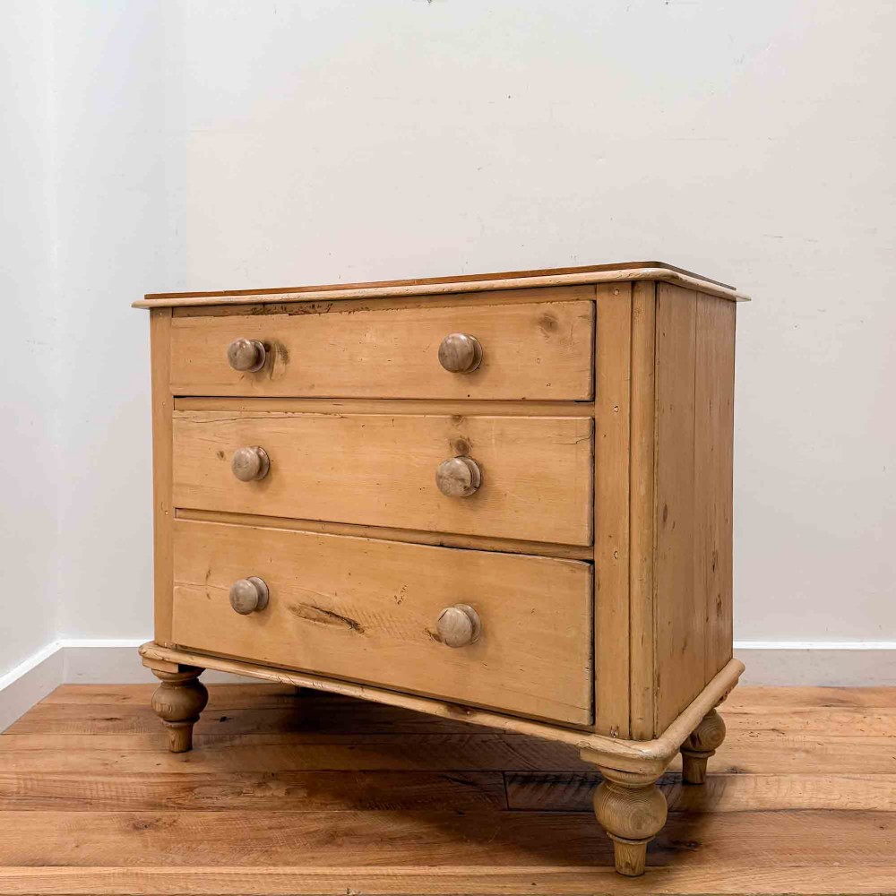 A natural light pine chest of drawers featuring three full-width drawers with turned wooden knobs, rounded front column edges, and turned bun feet. View II