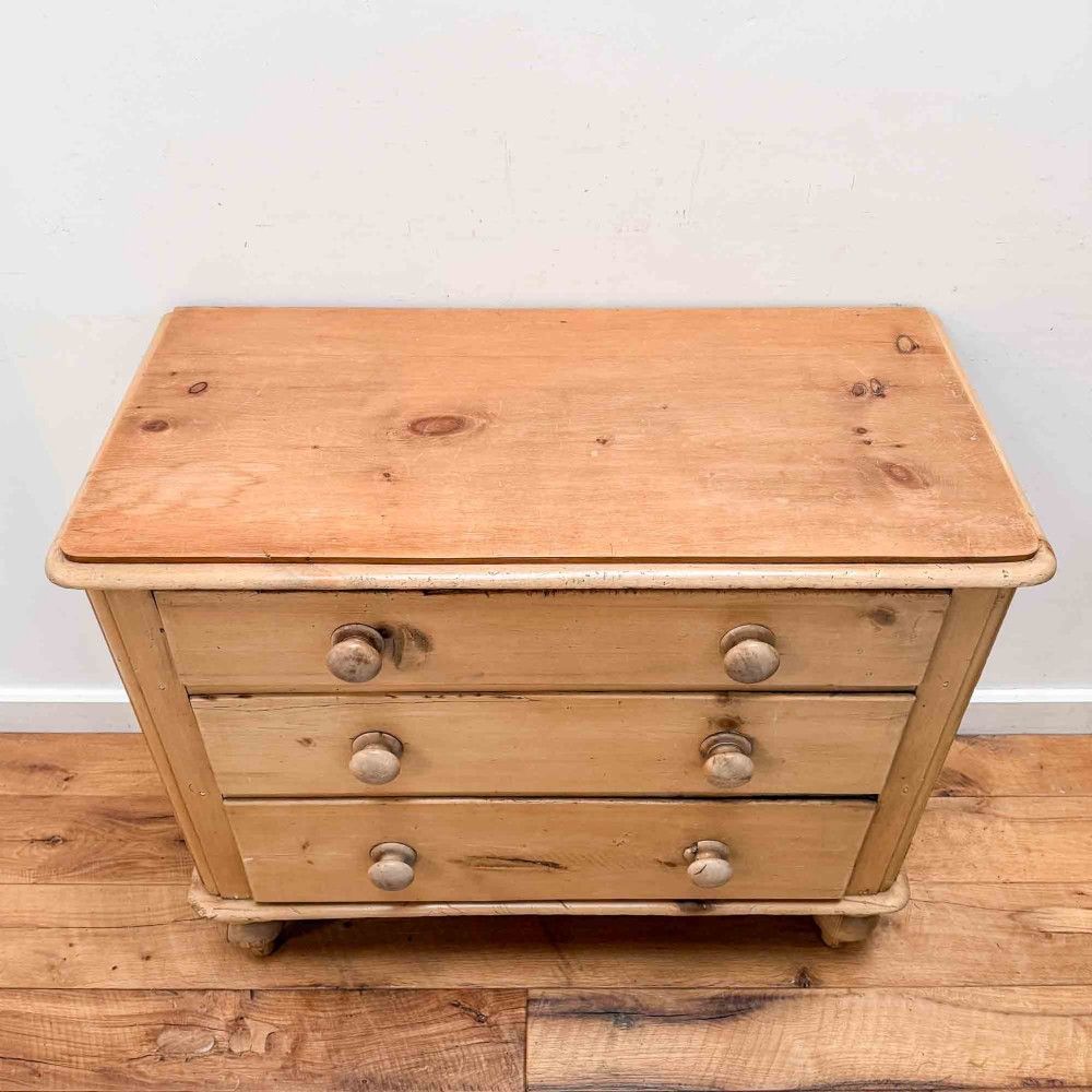 A natural light pine chest of drawers featuring three full-width drawers with turned wooden knobs, rounded front column edges, and turned bun feet. View III