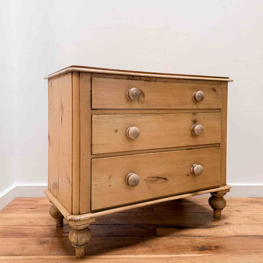 A natural light pine chest of drawers featuring three full-width drawers with turned wooden knobs, rounded front column edges, and turned bun feet. View VII
