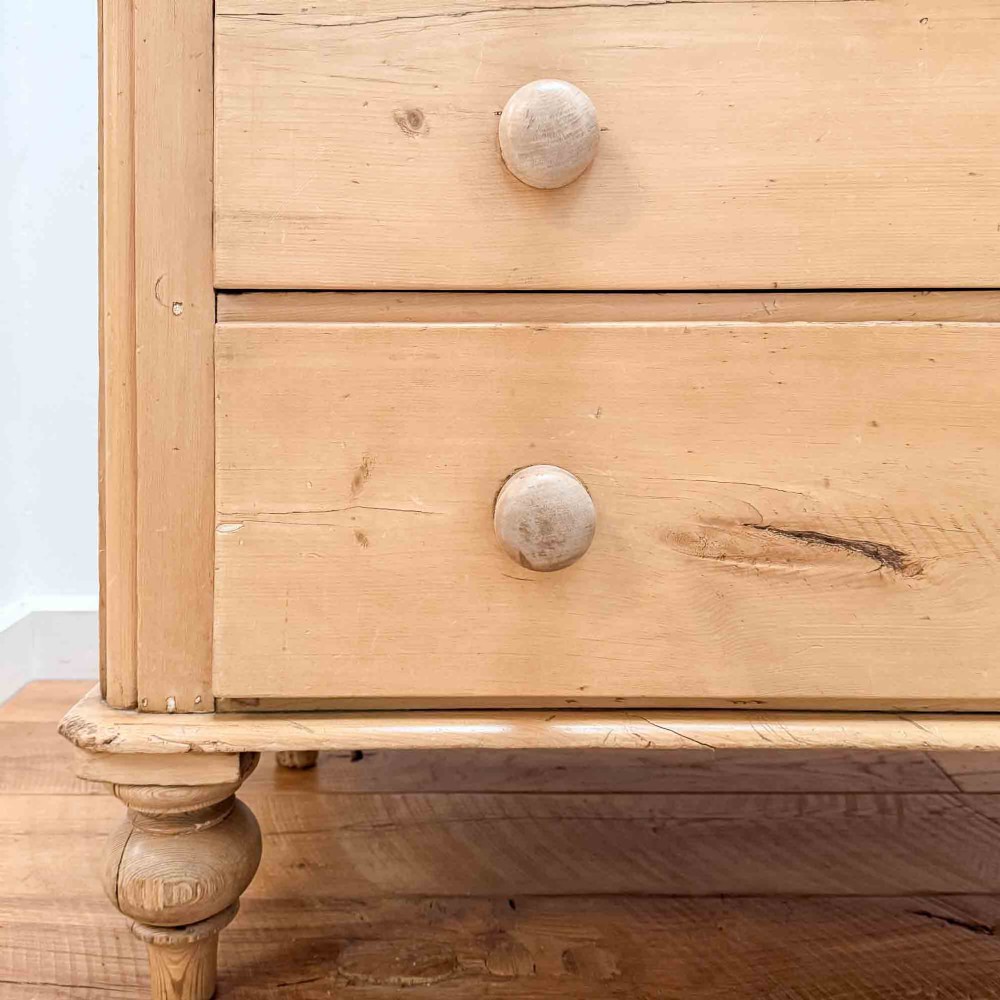 A natural light pine chest of drawers featuring three full-width drawers with turned wooden knobs, rounded front column edges, and turned bun feet. View X