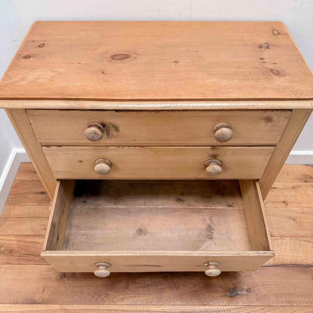 A natural light pine chest of drawers featuring three full-width drawers with turned wooden knobs, rounded front column edges, and turned bun feet. View XIII