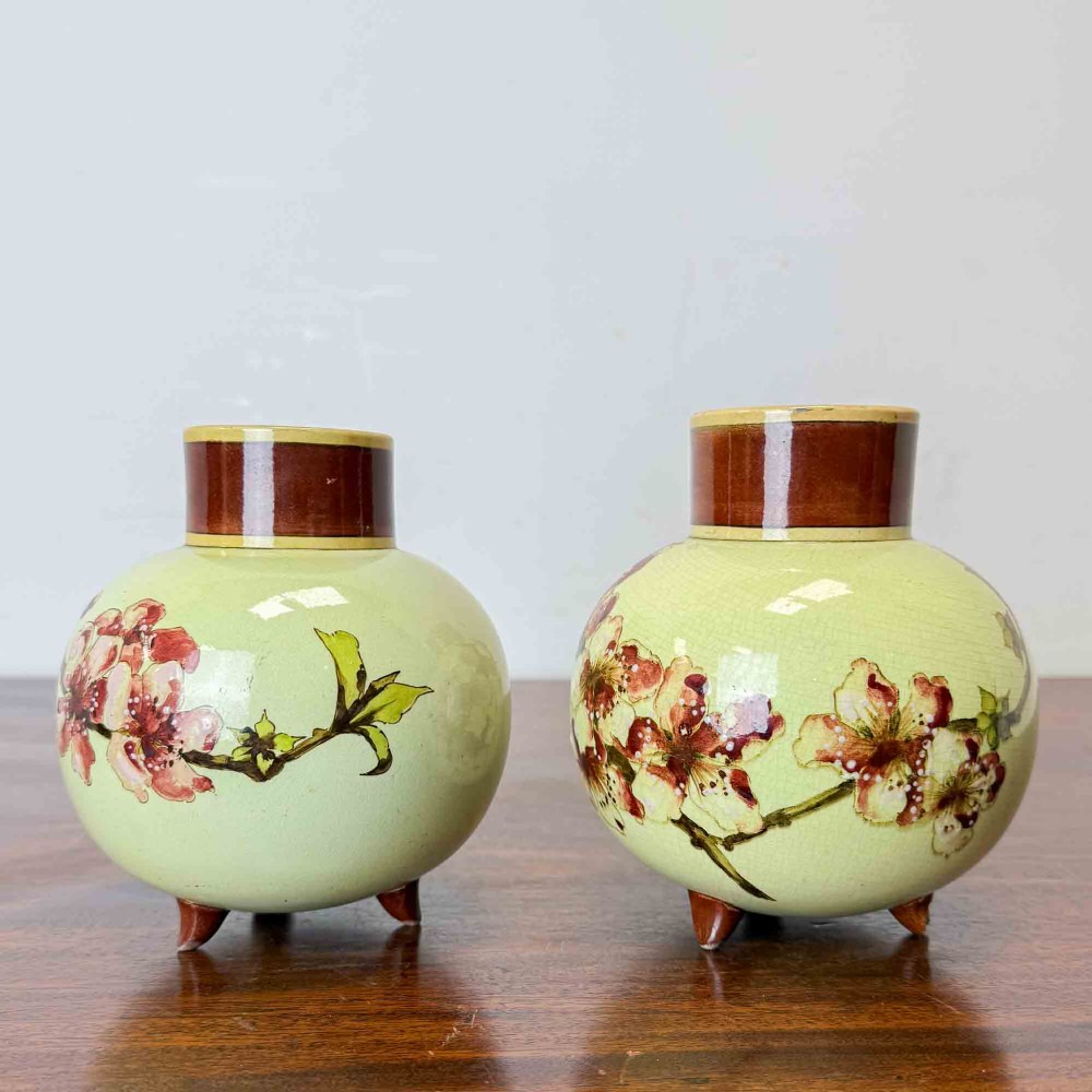 A pair of round pale green ceramic vases with hand-painted pink cherry blossom branches, dark brown collars, and small tripod feet. View III