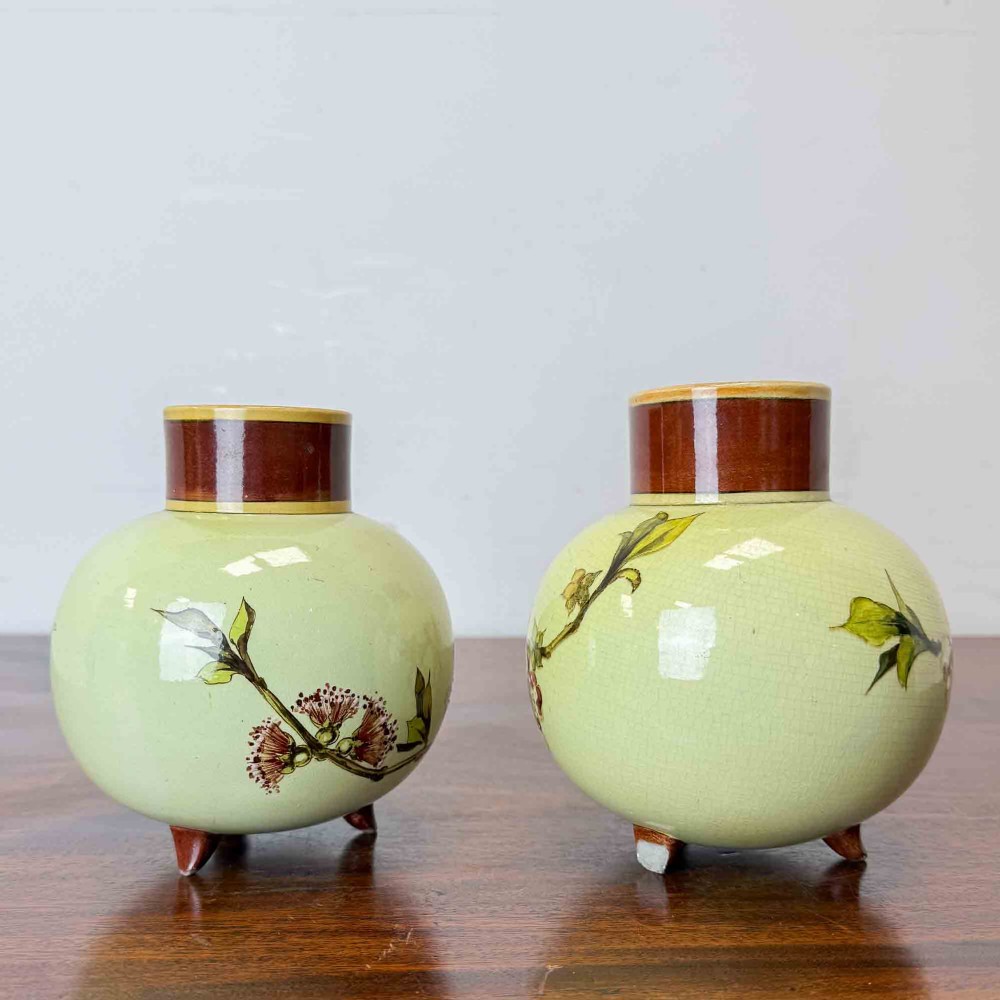 A pair of round pale green ceramic vases with hand-painted pink cherry blossom branches, dark brown collars, and small tripod feet. View IV