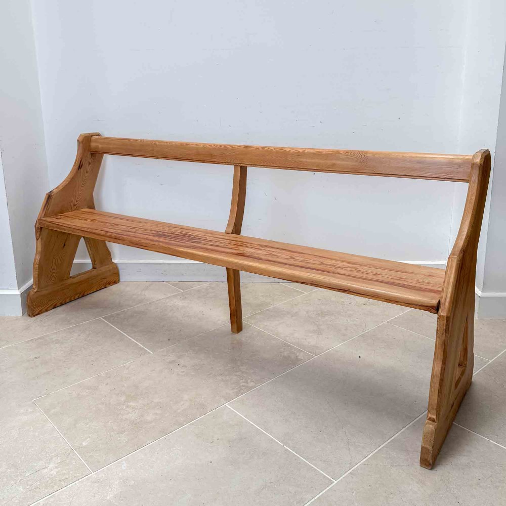 An antique pitch pine open back church pew featuring shaped side supports and a single central back support. View III