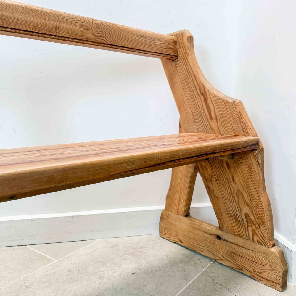 An antique pitch pine open back church pew featuring shaped side supports and a single central back support. View VI