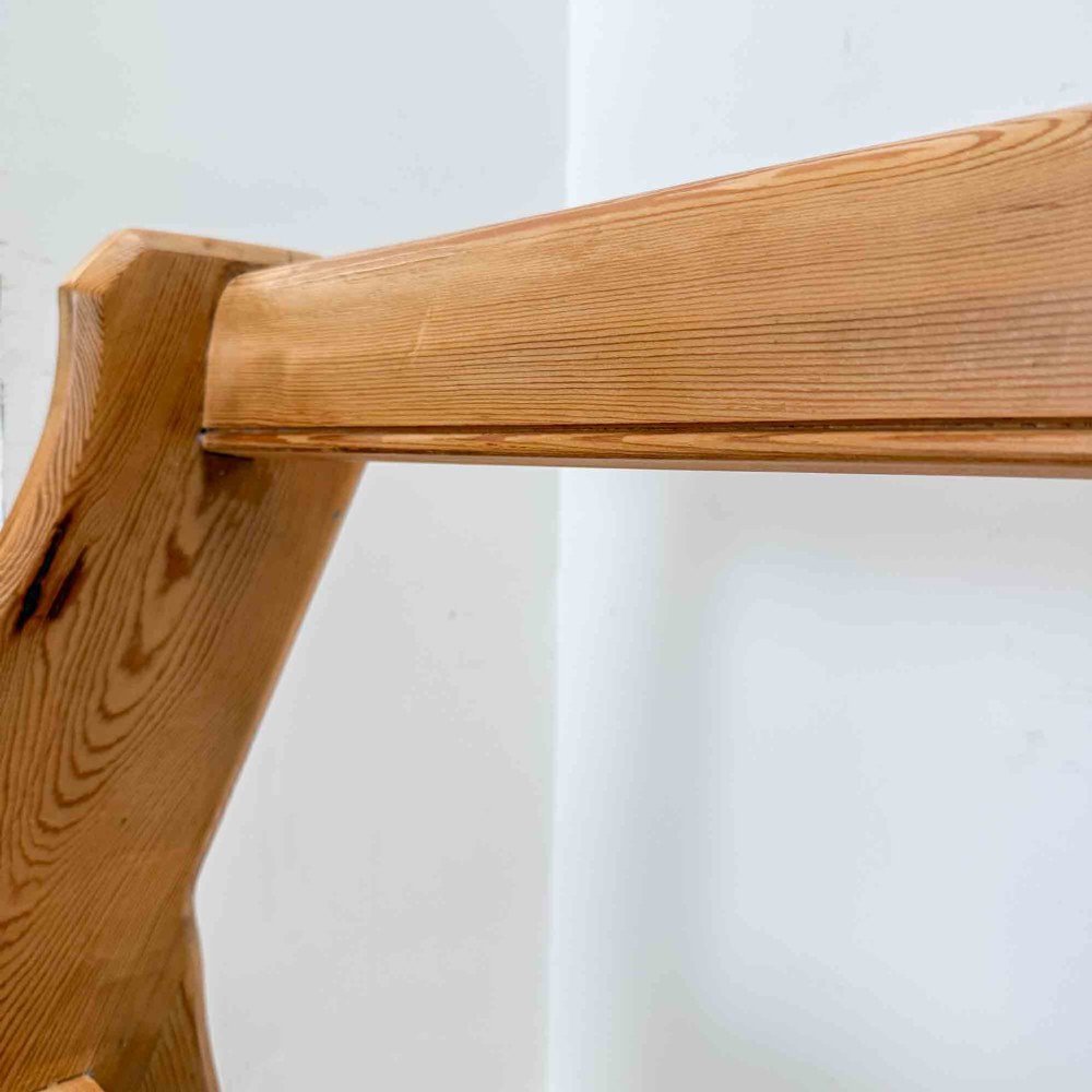 An antique pitch pine open back church pew featuring shaped side supports and a single central back support. View IX