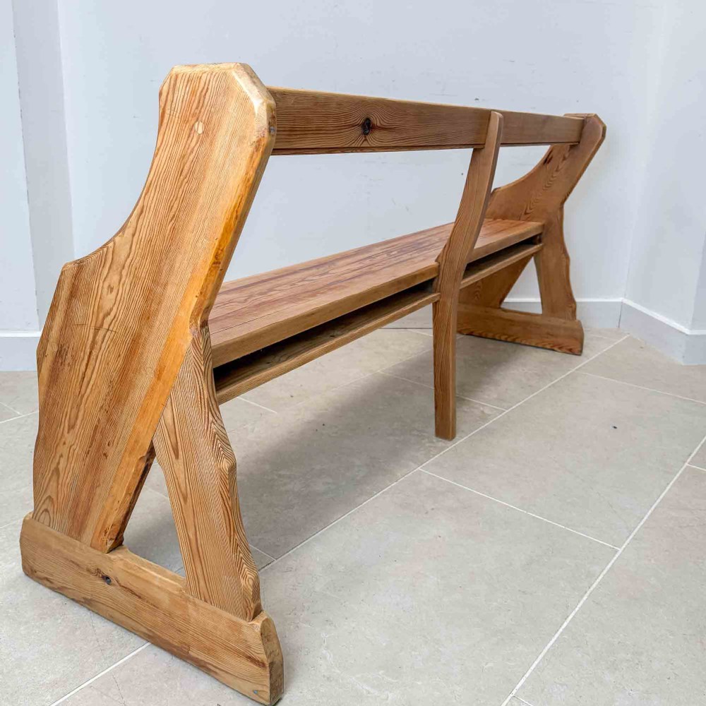 An antique pitch pine open back church pew featuring shaped side supports and a single central back support. View X