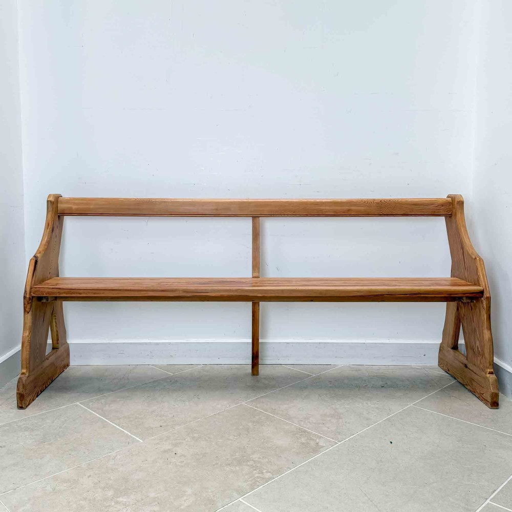 An antique pitch pine open back church pew featuring shaped side supports and a single central back support. View XII