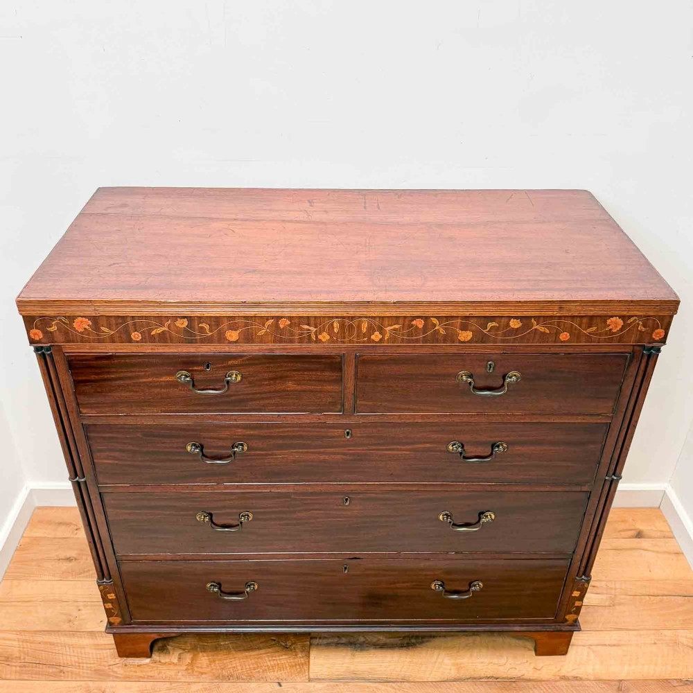 An antique mahogany chest of drawers with two short over three long drawers and floral inlay details along the upper frieze. View VII
