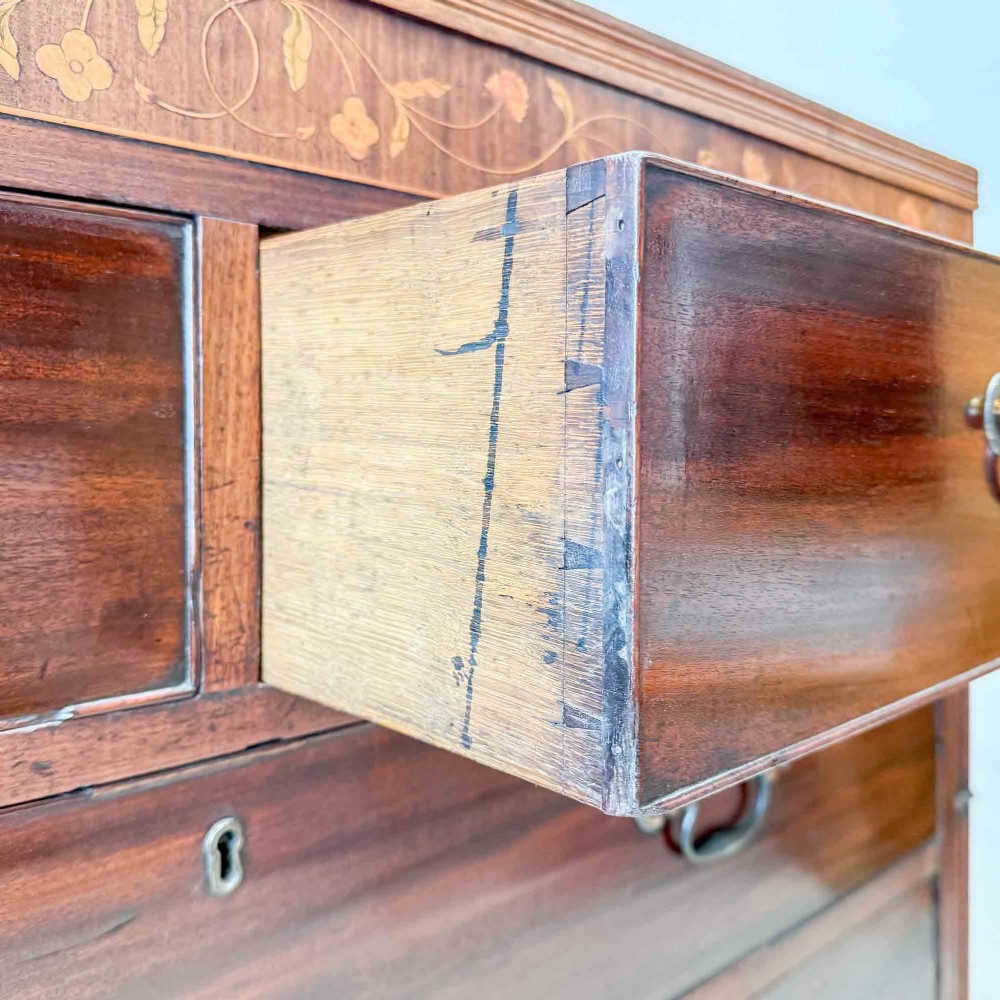 An antique mahogany chest of drawers with two short over three long drawers and floral inlay details along the upper frieze. View XIII