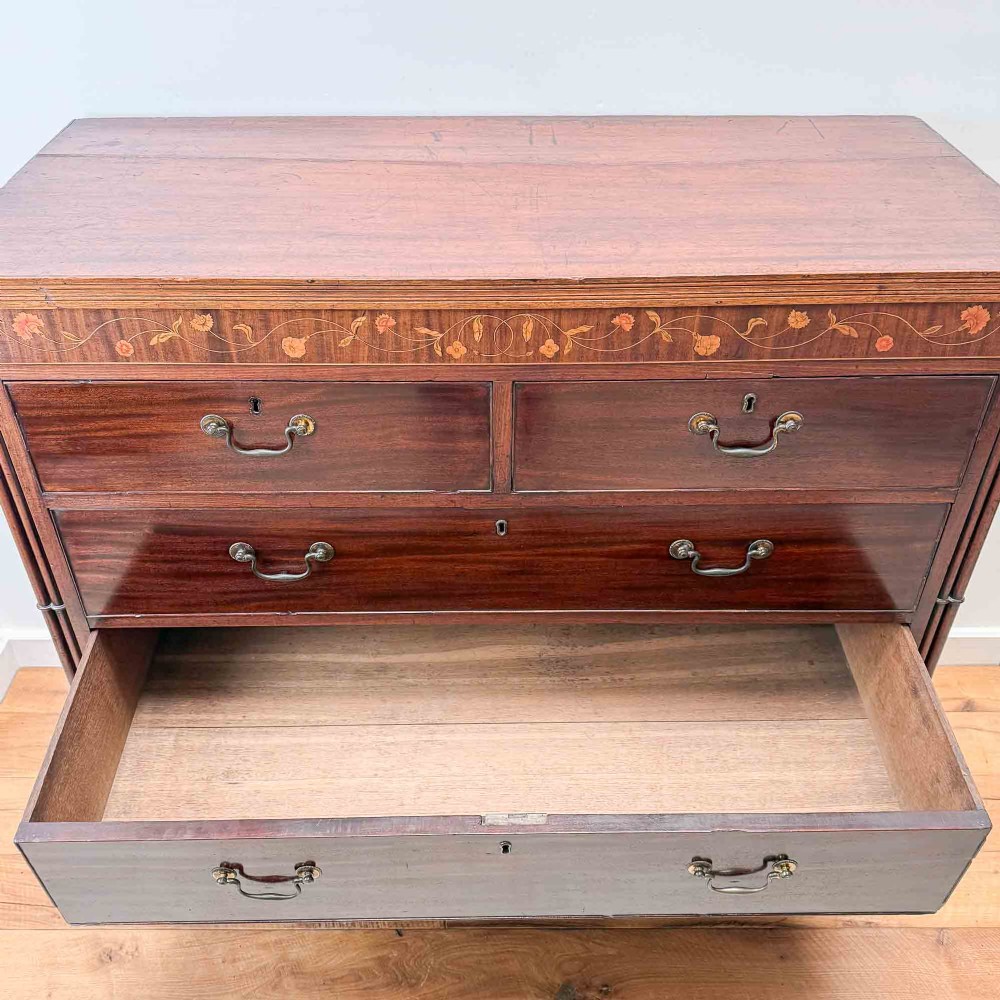 An antique mahogany chest of drawers with two short over three long drawers and floral inlay details along the upper frieze. View XIV