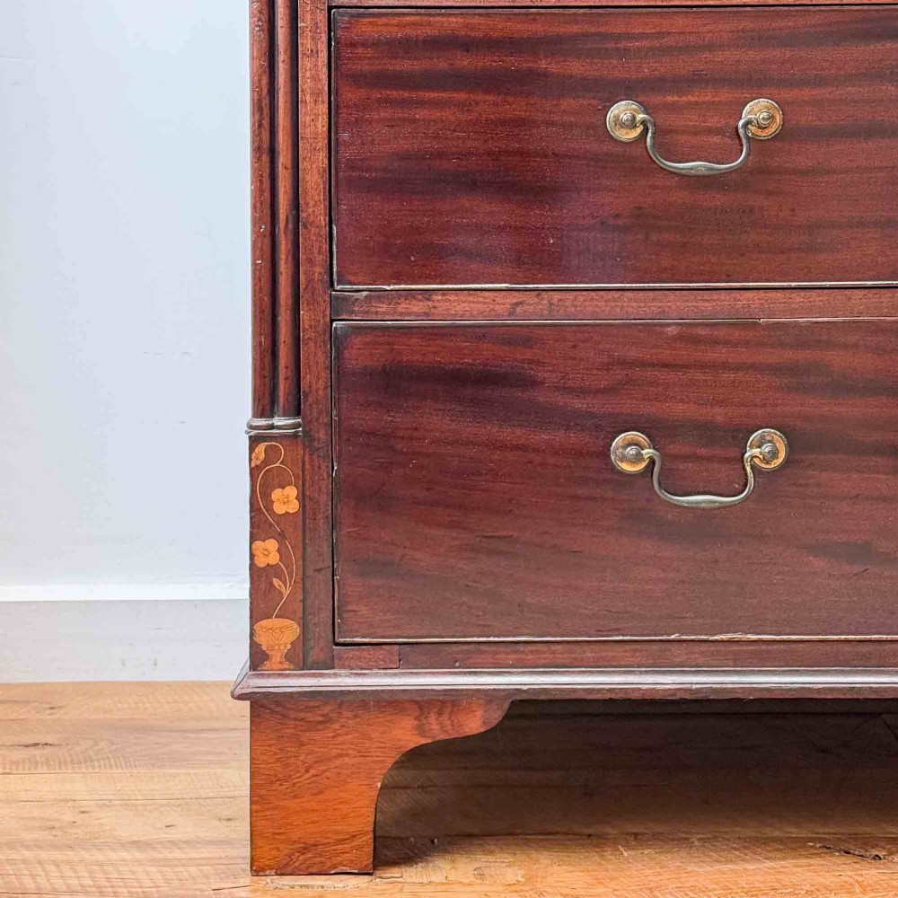 An antique mahogany chest of drawers with two short over three long drawers and floral inlay details along the upper frieze. View XV