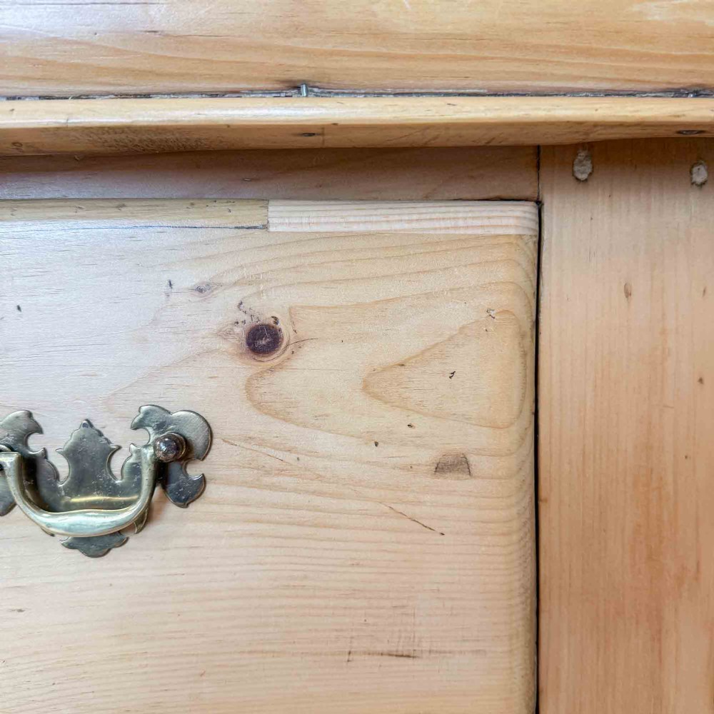 A Victorian natural pine dresser base featuring a low upstand back, seven drawers with metal drop handles, and turned bun feet. View IX