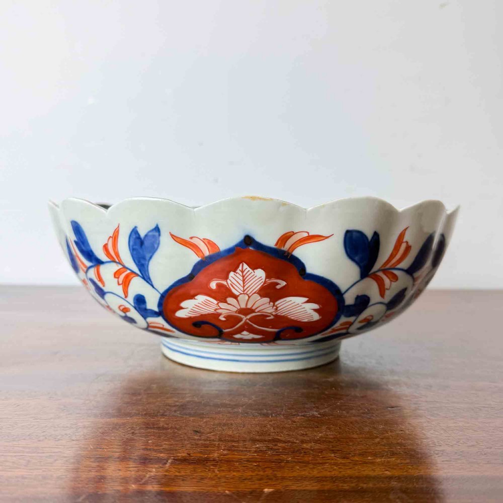 A shallow Japanese Imari porcelain bowl featuring a scalloped rim, hand-painted floral panels in cobalt blue, iron-red enamel, and green accents on a white porcelain ground. View II