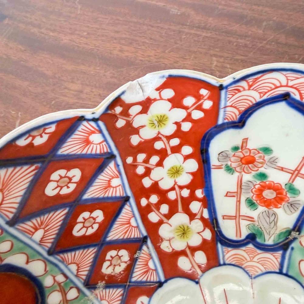 A shallow Japanese Imari porcelain bowl featuring a scalloped rim, hand-painted floral panels in cobalt blue, iron-red enamel, and green accents on a white porcelain ground. View VIII