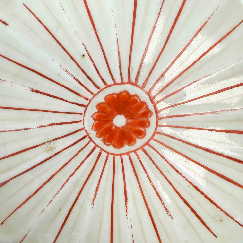 A shallow Japanese Imari porcelain bowl featuring a scalloped rim, hand-painted floral panels in cobalt blue, iron-red enamel, and green accents on a white porcelain ground. View IX
