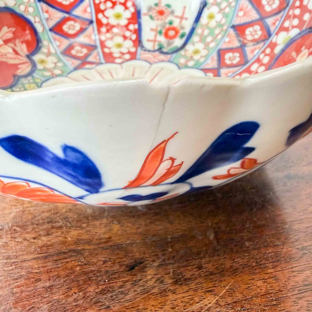 A shallow Japanese Imari porcelain bowl featuring a scalloped rim, hand-painted floral panels in cobalt blue, iron-red enamel, and green accents on a white porcelain ground. View XI