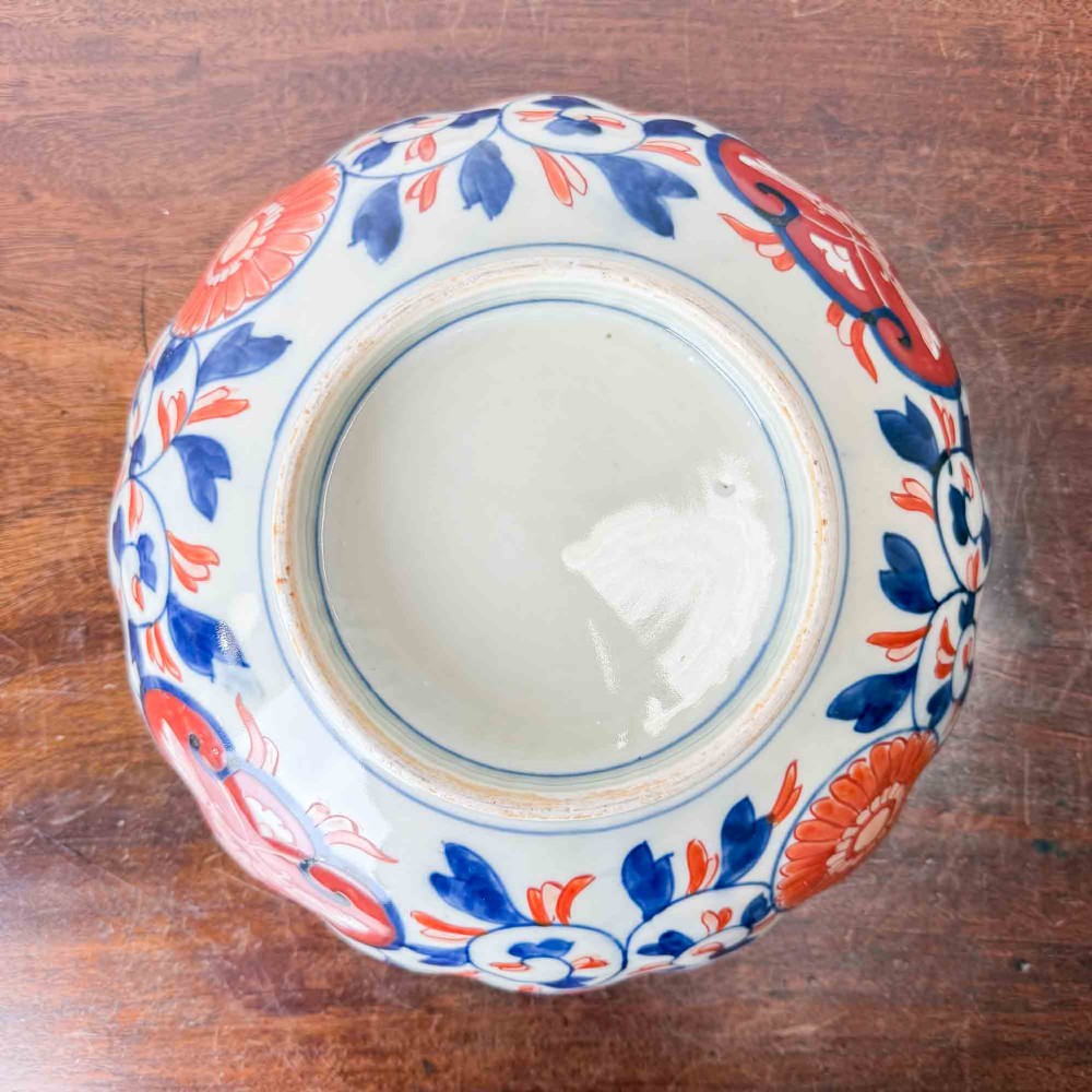 A shallow Japanese Imari porcelain bowl featuring a scalloped rim, hand-painted floral panels in cobalt blue, iron-red enamel, and green accents on a white porcelain ground. View XII