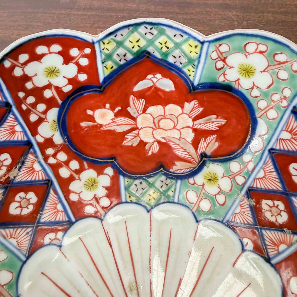 A shallow Japanese Imari porcelain bowl featuring a scalloped rim, hand-painted floral panels in cobalt blue, iron-red enamel, and green accents on a white porcelain ground. View XIV