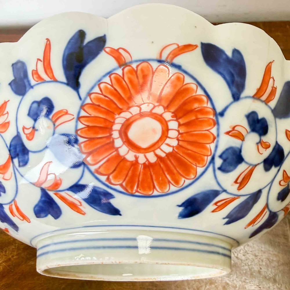 A shallow Japanese Imari porcelain bowl featuring a scalloped rim, hand-painted floral panels in cobalt blue, iron-red enamel, and green accents on a white porcelain ground. View XV