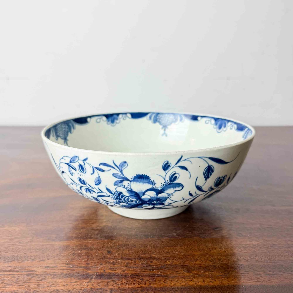 An 18th-century circular soft-paste porcelain bowl featuring hand-painted cobalt blue floral motifs on a white background.