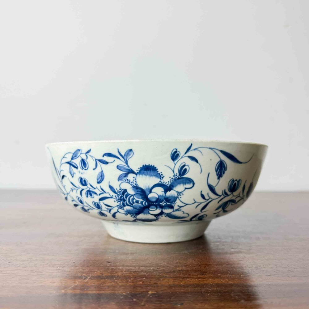 An 18th-century circular soft-paste porcelain bowl featuring hand-painted cobalt blue floral motifs on a white background. View II