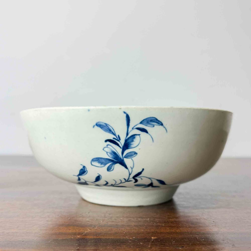 An 18th-century circular soft-paste porcelain bowl featuring hand-painted cobalt blue floral motifs on a white background. View IV