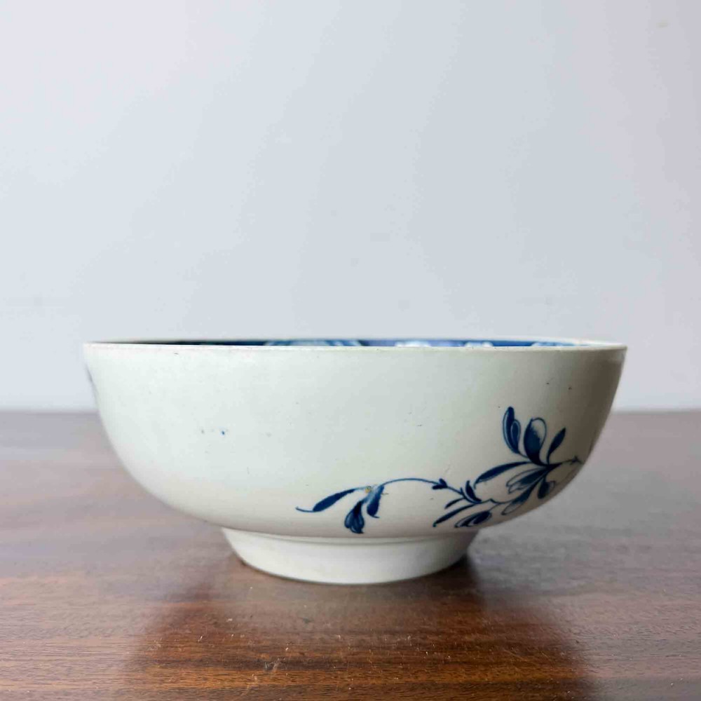 An 18th-century circular soft-paste porcelain bowl featuring hand-painted cobalt blue floral motifs on a white background. View V