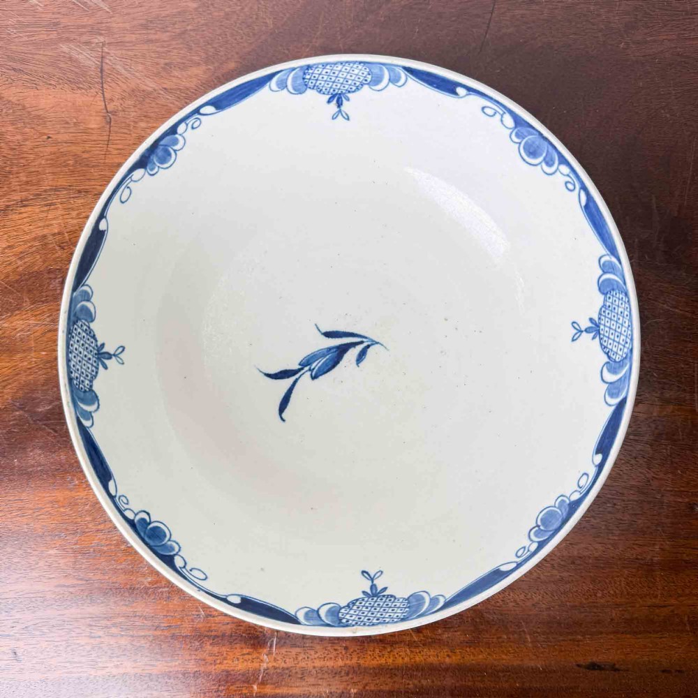 An 18th-century circular soft-paste porcelain bowl featuring hand-painted cobalt blue floral motifs on a white background. View VII