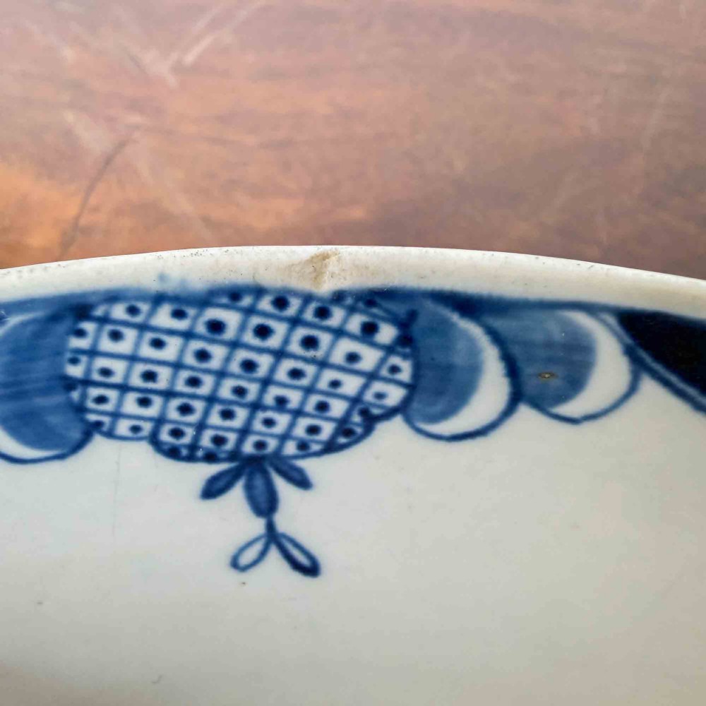An 18th-century circular soft-paste porcelain bowl featuring hand-painted cobalt blue floral motifs on a white background. View IX