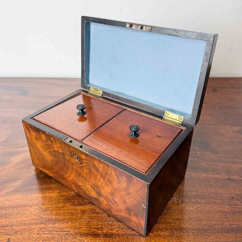 A rectangular early Victorian tea caddy crafted from flame mahogany veneer with crossbanded inlaid borders and a central metal keyhole escutcheon. View IV
