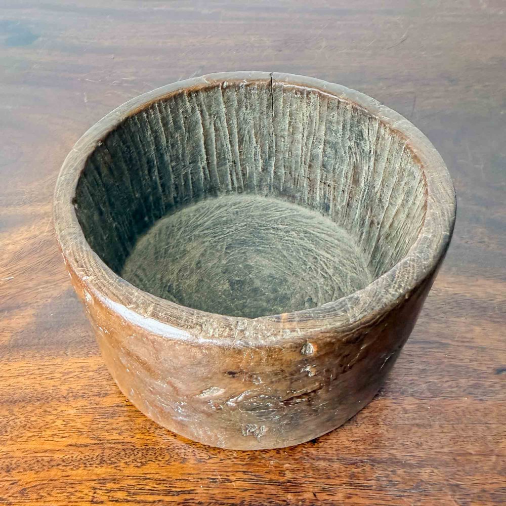 A round hand-carved antique wooden bowl with thick walls and a patinated brown timber surface. View III