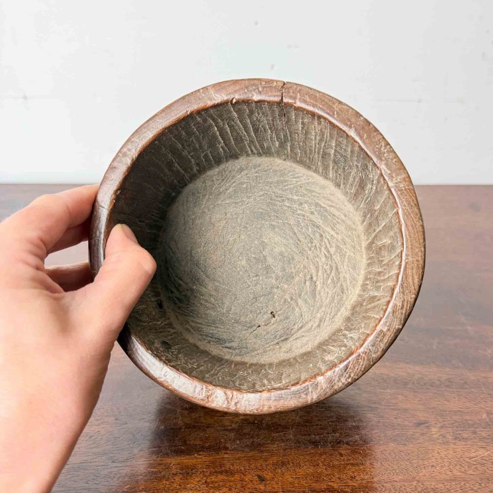A round hand-carved antique wooden bowl with thick walls and a patinated brown timber surface. View IV