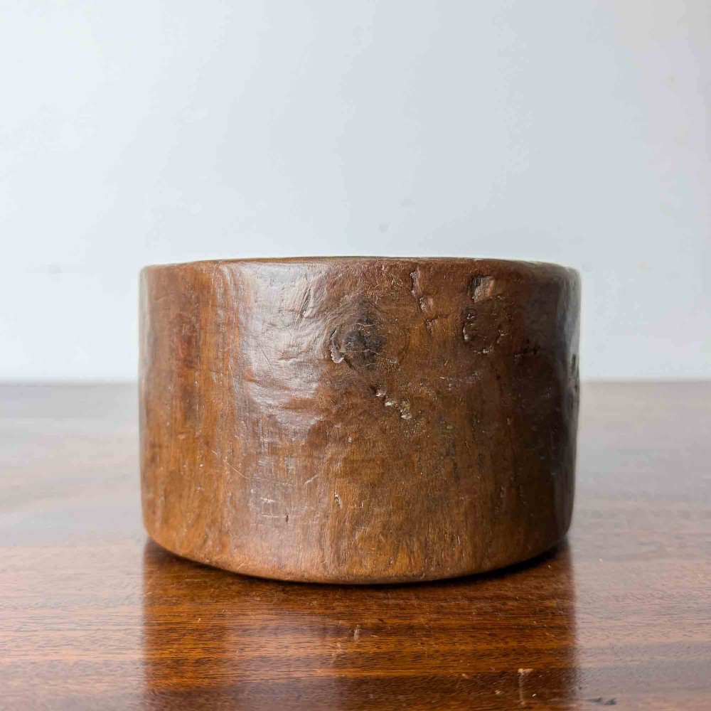A round hand-carved antique wooden bowl with thick walls and a patinated brown timber surface. View VI