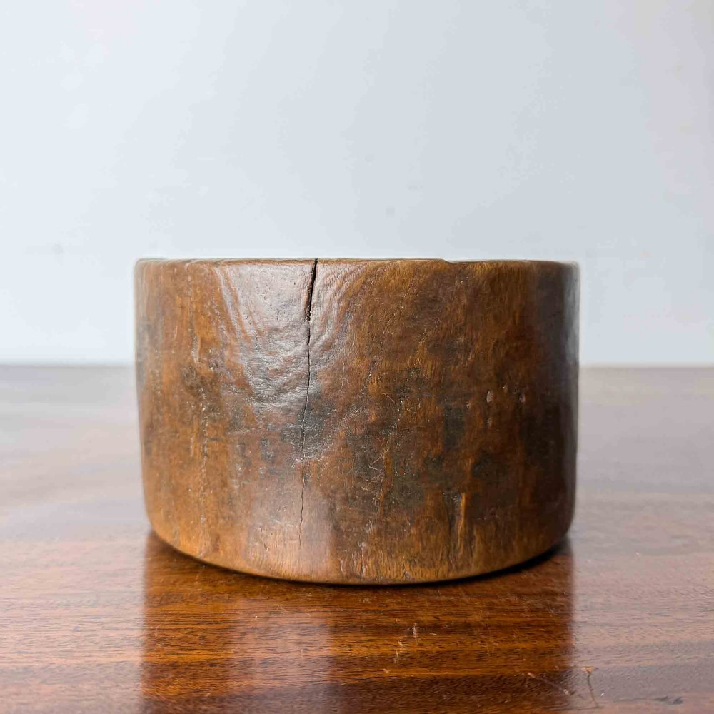 A round hand-carved antique wooden bowl with thick walls and a patinated brown timber surface. View VII