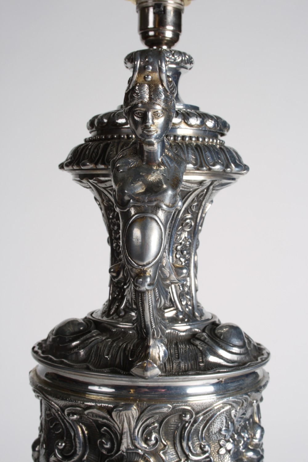 A polished silver-toned spelter table lamp base in the shape of a classical urn with relief carvings and creature handles on a circular marble plinth. View IX
