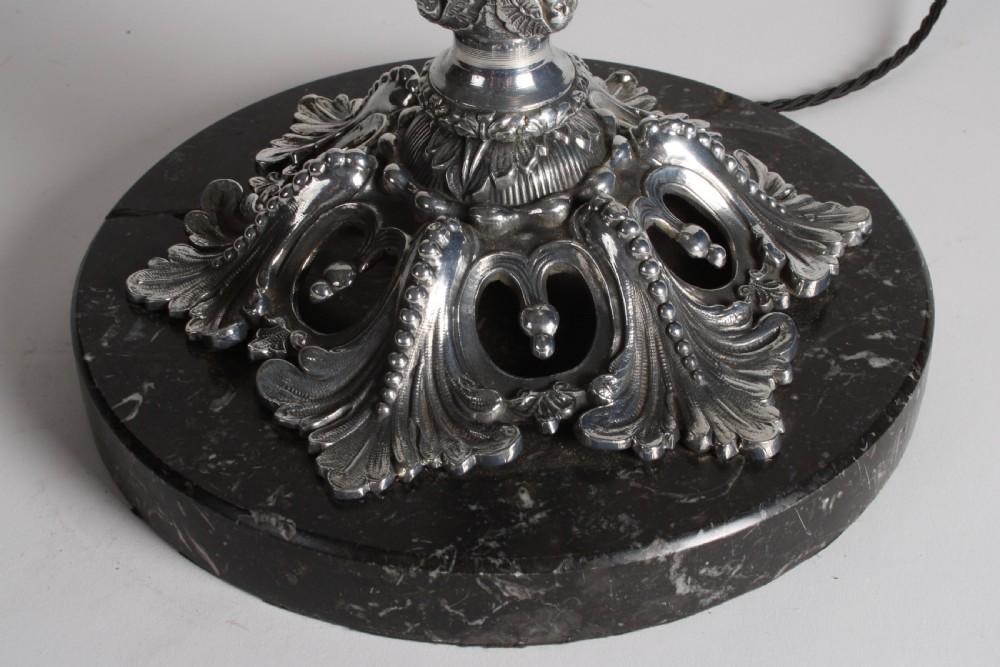 A polished silver-toned spelter table lamp base in the shape of a classical urn with relief carvings and creature handles on a circular marble plinth. View XIII