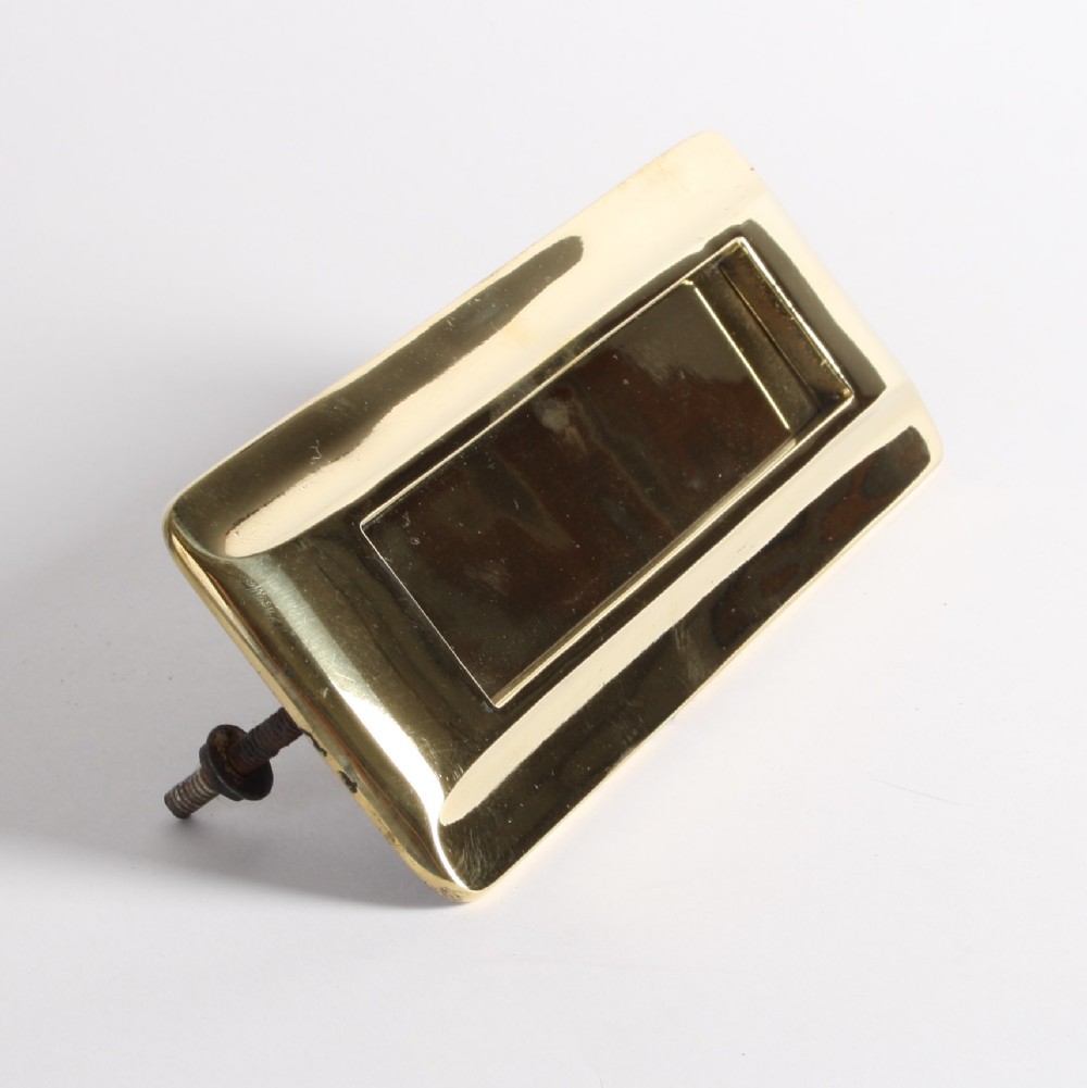 A solid polished brass Art Deco letterbox plate featuring a central rectangular flap within a streamlined bevelled frame.